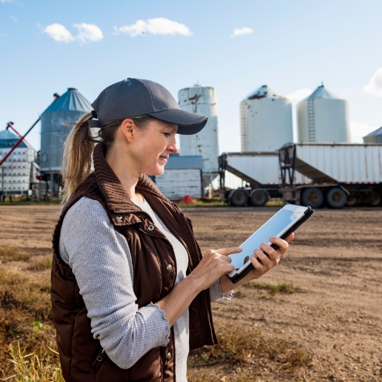 Mature Ag Woman With a Tablet in Front of a Co-op