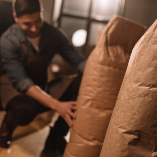 Man Kneeling Next to Large Bag of Agriculture Goods